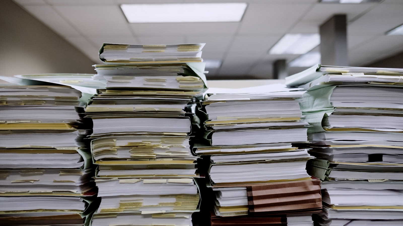Stacked paper files and document folders on a desk